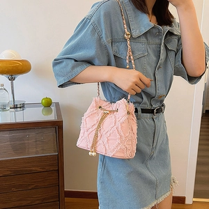 Vue détaillée du sac seau en denim rose avec bords effilochés et bandoulière perle