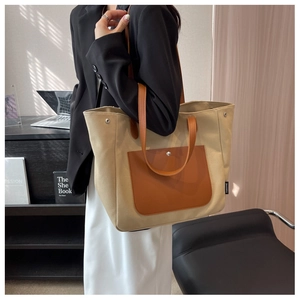 Detail of canvas tote bag with brown leather handles and side pocket in office setting