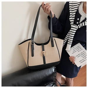 Detail of woven tote bag featuring black leather trim and elegant golden turn-lock closure