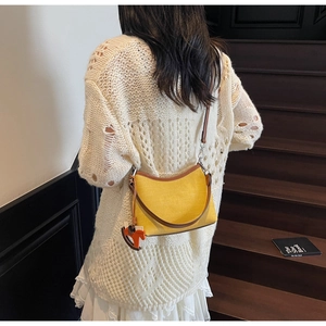 Detail of yellow canvas shoulder bag with brown leather trim and horse charm