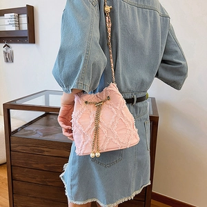 Sac seau en tweed rose avec chaîne dorée et détails de perles sur tenue en denim