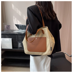 Detail of canvas tote bag with brown leather accents shown in a workplace setting