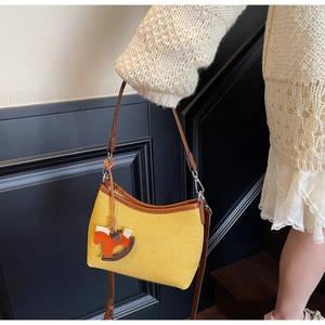 Detail of yellow fabric small square bag with leather trim and horse charm on model