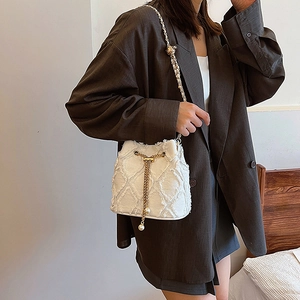 Détail du sac seau en tweed blanc avec chaîne dorée et élégante perle de serrage