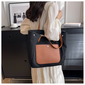 Detail of canvas tote bag with brown leather pocket and metal rivets on model back