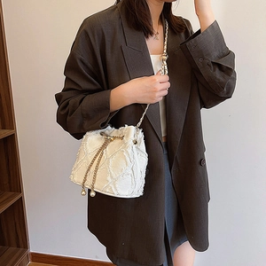 Détail du sac seau en tweed blanc avec chaîne dorée et charms de cordon en perles élégants
