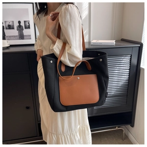 Detail of canvas tote bag with black body and brown leather pocket for daily use