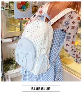 Polka dot backpack detail showing side pocket and decorative bow in a cafe setting