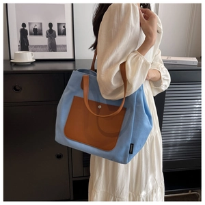 Detail of blue canvas tote bag with brown leather pocket and YUNXIANZ brand label