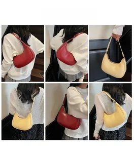 Detail view of burgundy and beige crescent bags with adjustable shoulder straps on model