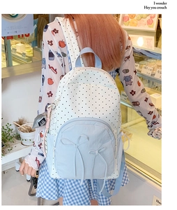 Girl wearing a polka dot backpack with blue accents and bow details in a cozy cafe setting
