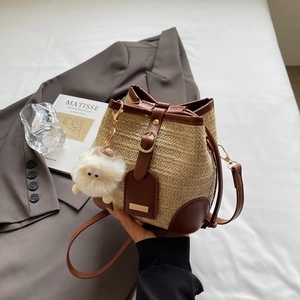 Sac seau en paille bicolore avec garniture en cuir marron et breloque pompon doux