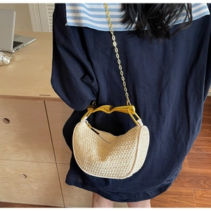 Detail of beige woven half-moon bag with golden metal handle and chain strap on shoulder