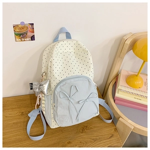 Polka dot school backpack detail with blue front pocket and ribbon bow charms