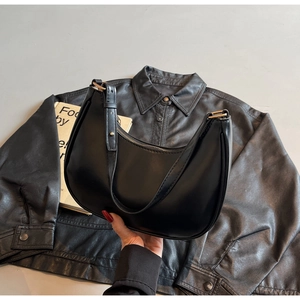 Detail of the black crescent bag with smooth leather texture and gold metal buckle