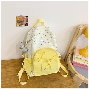 Close-up of polka dot backpack with yellow accents and decorative bow charms