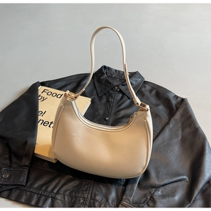 Chic beige leather hobo bag with zipper closure placed on a stylish black leather jacket