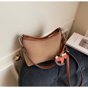 Close-up of vintage canvas underarm bag with leather trim and horse charm detail