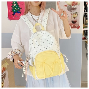 Detail view of polka dot backpack with yellow accents and a shiny bow charm
