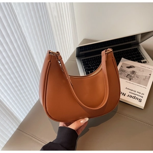 Detail of a brown crescent shoulder bag with golden zipper and smooth synthetic leather texture
