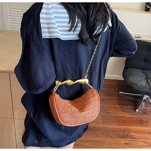 Close-up of woven half-moon handbag with gold twisted handle and metal chain strap
