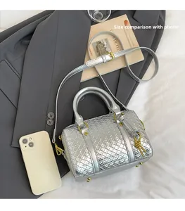 Silver woven Boston bag with gold hardware and shoulder strap shown with phone for scale