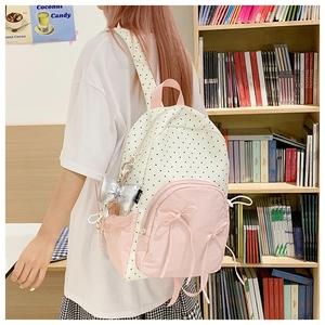 Detail view of polka dot backpack with pink pockets, bow accents and silver pendant charm