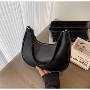 Close-up of black crescent shoulder bag with smooth texture and gold zipper details