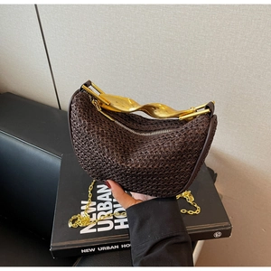 Detailed shot of dark brown woven handbag with a gold twisted metal handle and chain strap