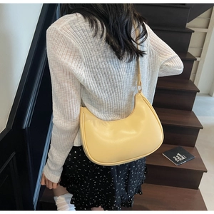 Detailed shoulder view of a yellow crescent hobo bag made of smooth synthetic leather