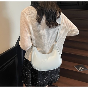 Back view of model wearing a light blue crescent shoulder bag on a wooden staircase