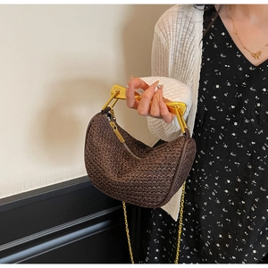 Macro view of woven raffia texture and golden metal handle on brown crescent handbag