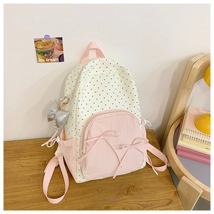 Detail of cute polka dot backpack featuring pink ribbon bows and silver bow keychain charm
