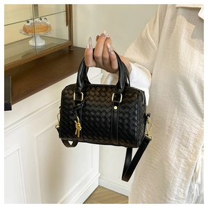 Detail of black woven mini Boston bag with golden knot pendant and leather handles