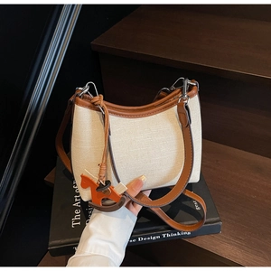 Detail of vintage canvas underarm bag with orange horse charm and brown leather strap