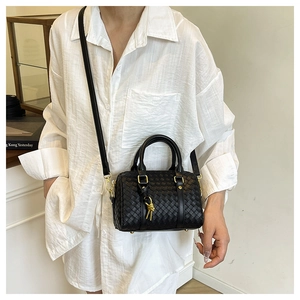 Detail of black woven leather boston bag with gold hardware and adjustable strap