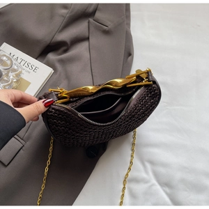 Detail view showing brown woven leather bag with gold wavy handle and interior compartment
