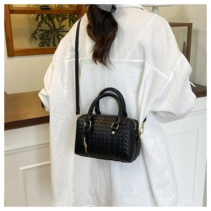 Close-up of black woven leather boston bag with gold hardware and cylindrical handles
