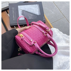 Detail of fuchsia woven cylindrical handbag with gold buckles and leather texture