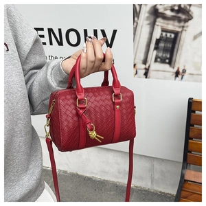 Detailed close-up of red woven leather Boston bag with gold knot hardware and top handles