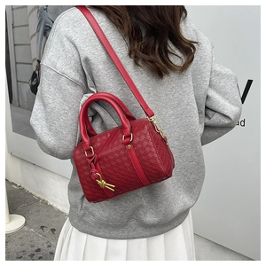 Detailed view of red woven leather Boston bag with gold hardware and shoulder strap