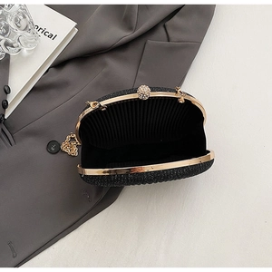 Macro view of black sequin evening bag featuring gold metal frame and ball clasp