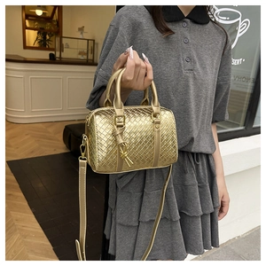Detailed view of gold woven texture crossbody bag with circular handles in a modern setting