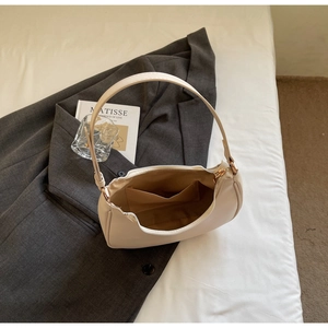 Detail view of the beige crescent bag showing the internal pocket and yellow lining