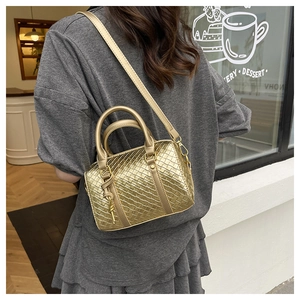 Detail of a gold woven Boston bag featuring metallic texture and detachable shoulder strap