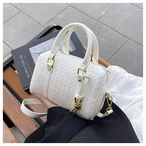 Detail shot of white woven leather texture on a square crossbody bag with gold hardware