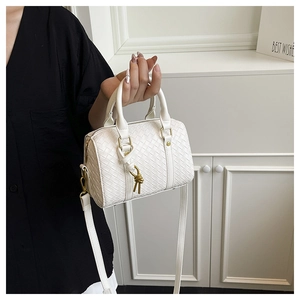 Detailed view of white woven texture on a classic Boston handbag with gold hardware