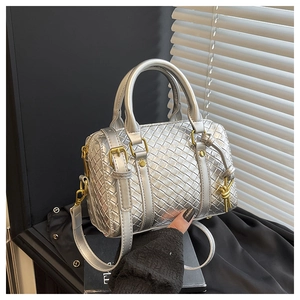 Macro shot of silver woven square bag with gold hardware and smooth metallic texture