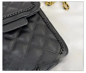 Gros plan sur la texture en cuir noir matelassé et les détails de chaîne de ce sac rétro