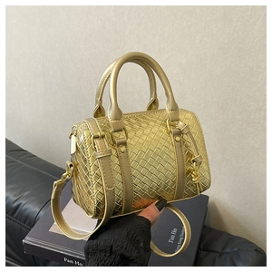 Macro detail of gold woven leather texture and handles on the Boston bag